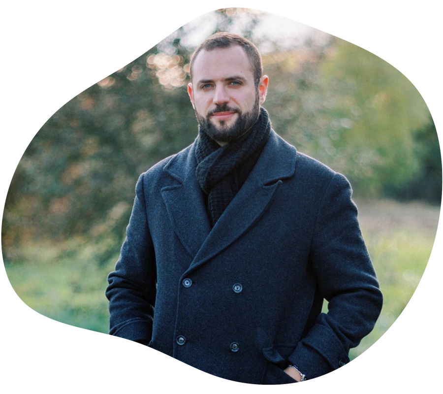 Mann steht im Freien und tr&auml;gt einen dunklen Mantel.